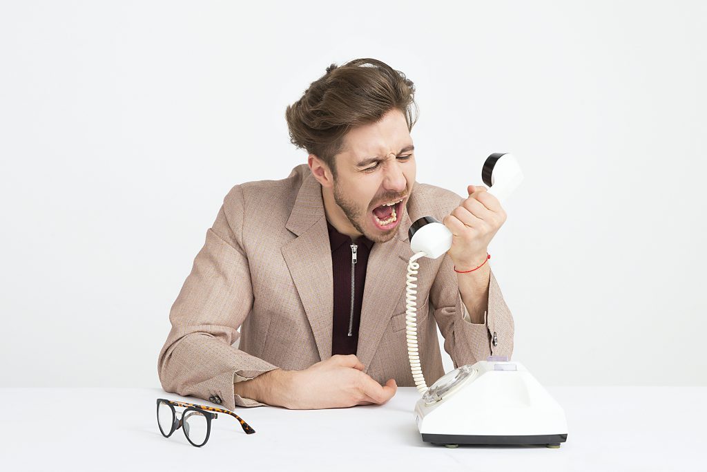 A man screaming into an old phone.